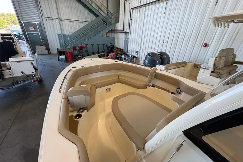 Slide: The Image of 2024 Scout 215 XSF boat interior with beige seating in a warehouse setting. - 12