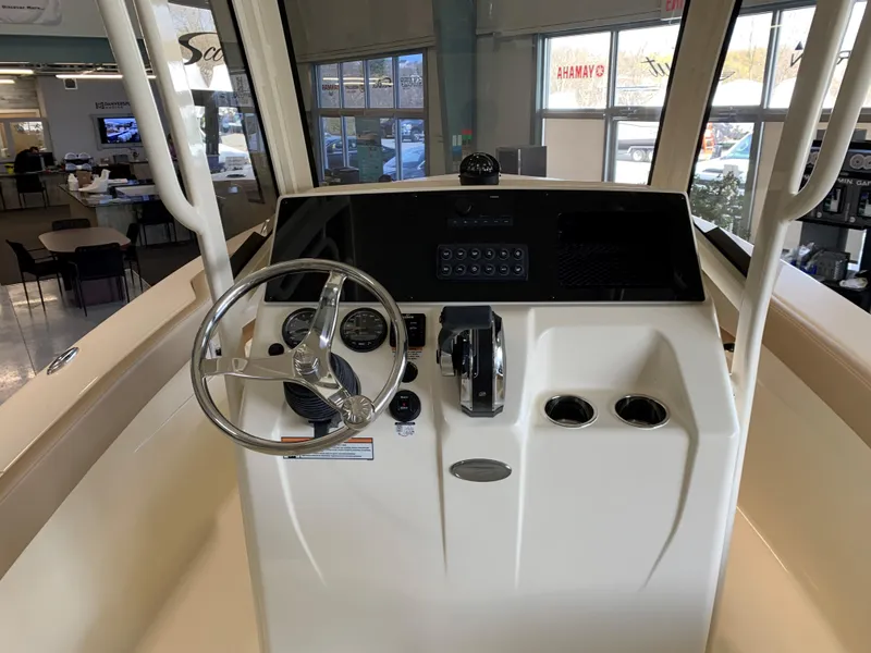 Slide: The Image of 2024 Scout 215 XSF boat in showroom, surrounded by other boats, ready for display. - 3