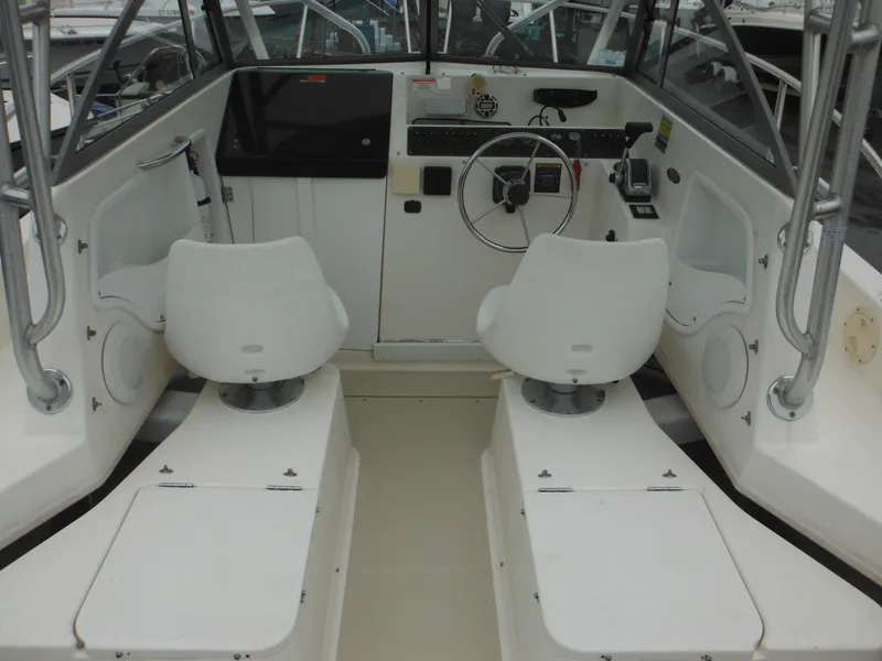 Slide: The Image of 1997 Robalo 2140 Walkaround boat cockpit with dual white captain chairs. - 10