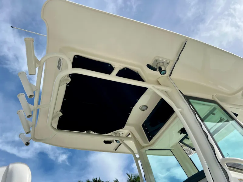 Slide: The Image of 2015 Boston Whaler 250 Outrage boat hardtop and rod holders against blue sky. - 13