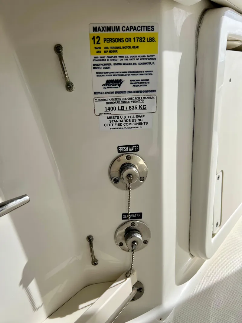 Slide: The Image of 2015 Boston Whaler 250 Outrage maximum capacities label and water connections. - 34