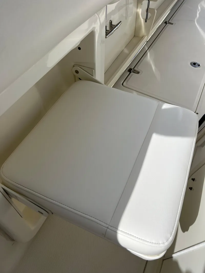 Slide: The Image of 2015 Boston Whaler 250 Outrage white cushioned seat and storage compartment. - 43