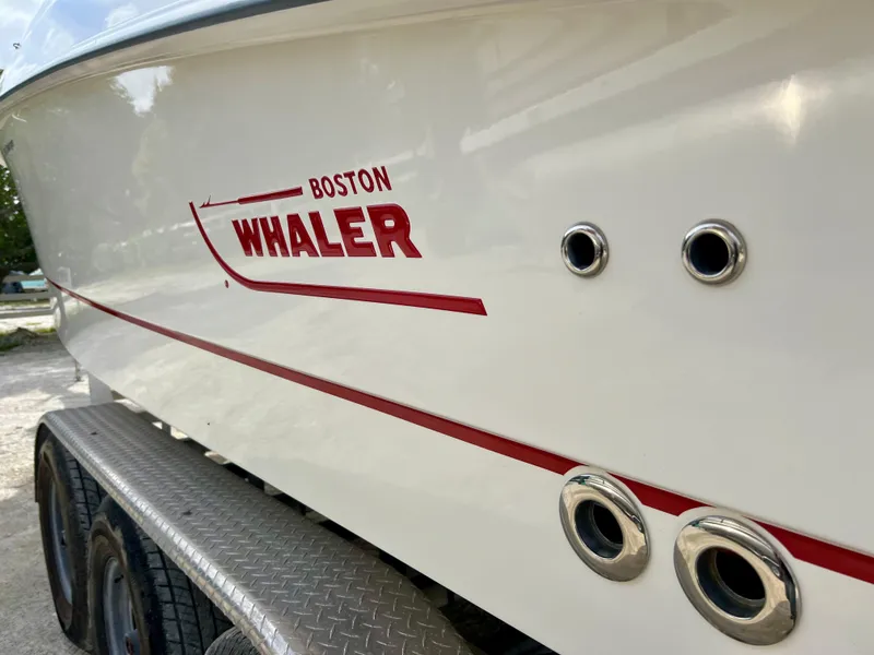 Slide: The Image of 2015 Boston Whaler 250 Outrage boat side view with logo and trailer. - 9