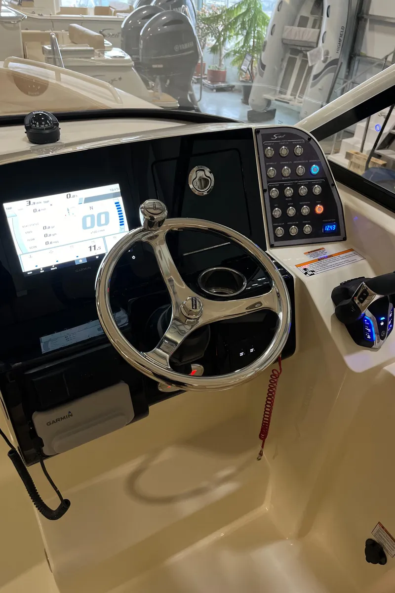 Slide: The Image of 2024 Scout 255 Dorado boat dashboard with steering wheel and control panel. - 13