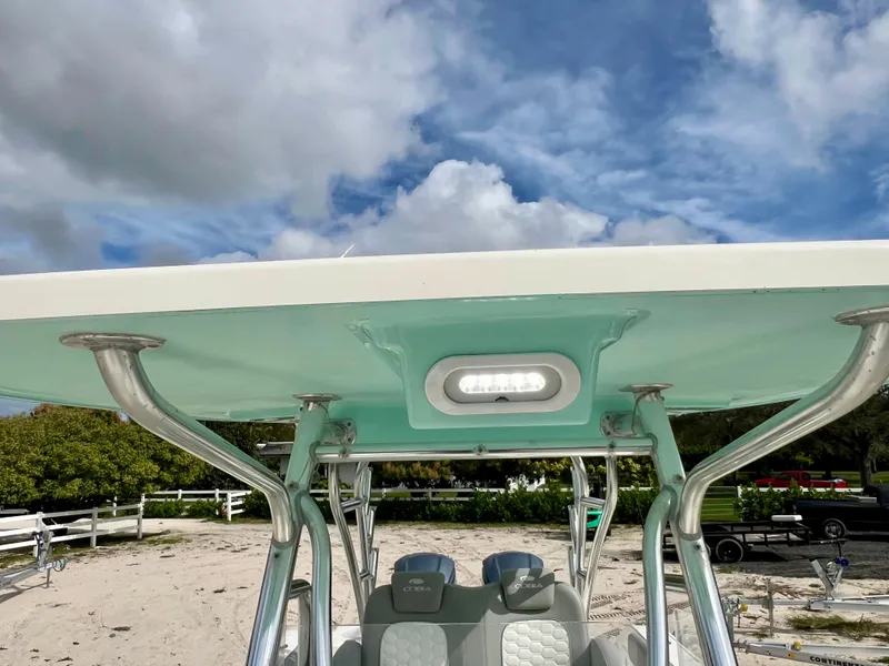 Slide: The Image of 2014 Cobia 296 Center Console boat with T-top and seating, parked on sandy shore. - 14