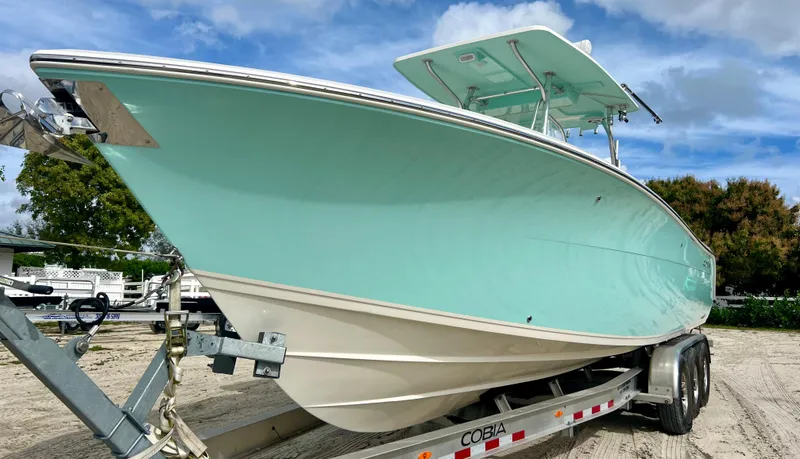 Slide: The Image of 2014 Cobia 296 Center Console boat on trailer, light blue hull, clear sky background. - 3