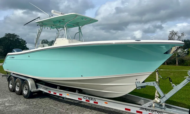 Slide: The Image of 2014 Cobia 296 Center Console boat on trailer, light blue hull, cloudy sky background. - 4