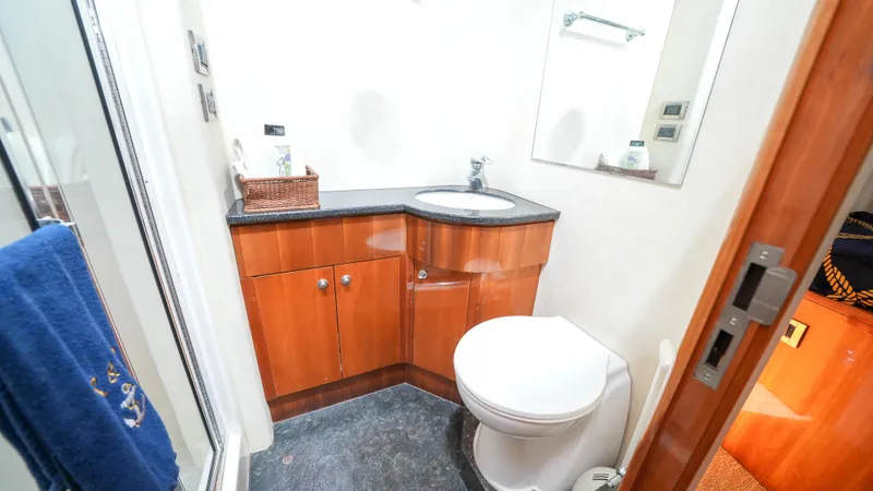 Slide: The Image of 2002 Queenship 70 Baretta yacht bathroom with wooden cabinetry and modern fixtures. - 20
