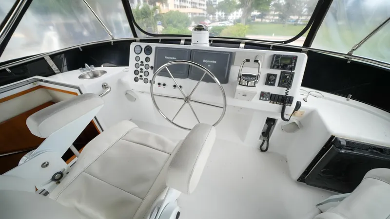 Slide: The Image of 2002 Queenship 70 Baretta yacht helm with modern navigation equipment and white leather seating. - 25