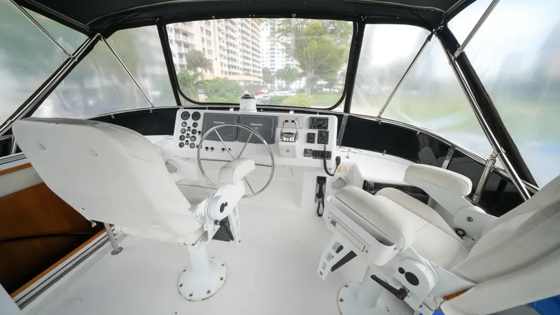 Slide: The Image of Cockpit of 2002 Queenship 70 Baretta yacht with white seating and control panel. - 26