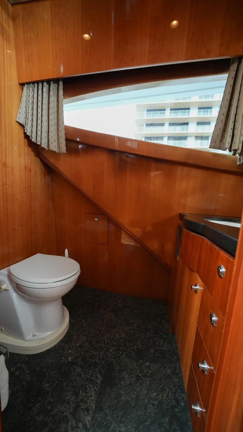 Slide: The Image of 2002 Queenship 70 Baretta yacht bathroom with wooden cabinetry and modern fixtures. - 6