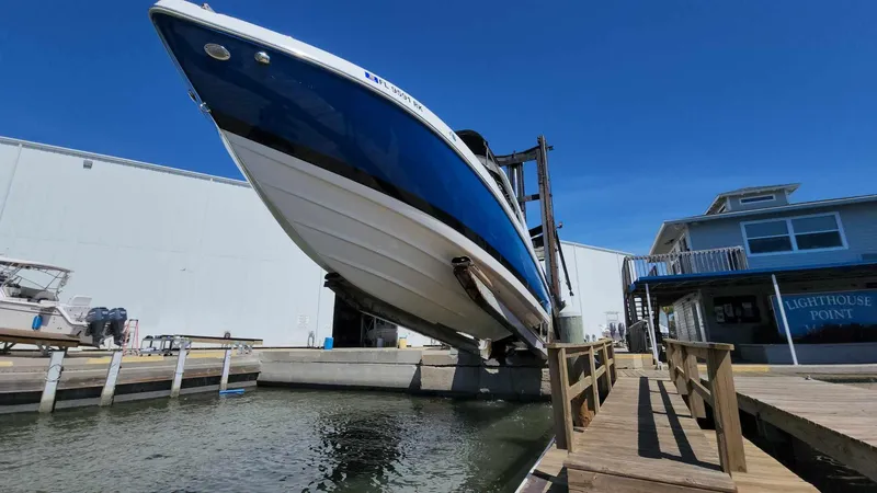 Slide: The Image of 2018 Rinker QX 26 boat being lifted at a marina dock. - 12