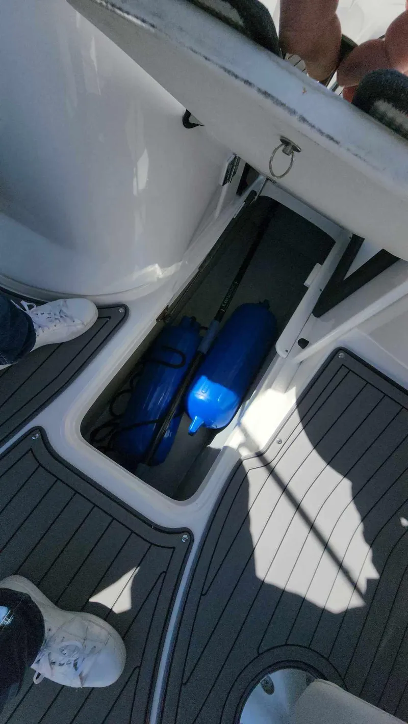 Slide: The Image of 2018 Rinker QX 26 boat storage compartment with blue fenders. - 13