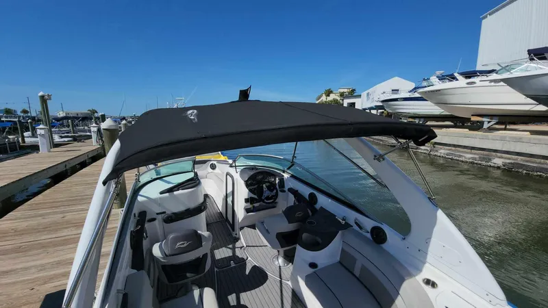 Slide: The Image of 2018 Rinker QX 26 boat docked at a marina with a black canopy. - 15