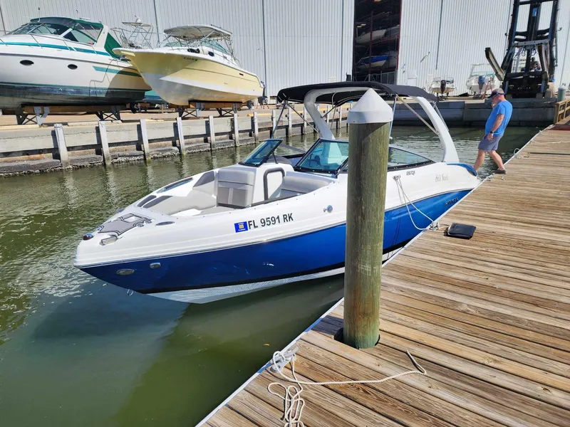 Slide: The Image of 2018 Rinker QX 26 boat docked at a marina with a man walking on the pier. - 19