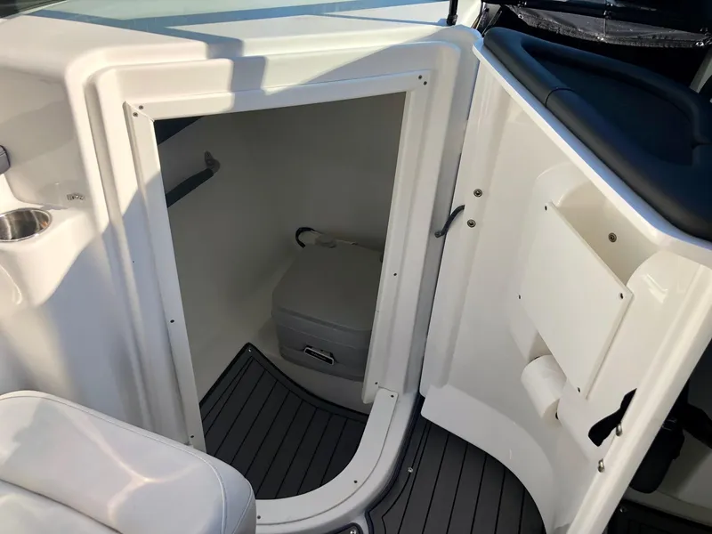 Slide: The Image of 2018 Rinker QX 26 boat interior with a compact toilet compartment. - 2