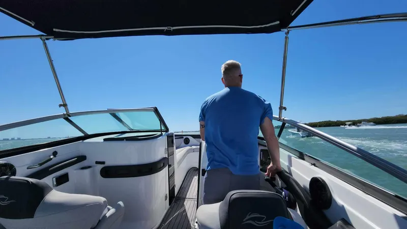 Slide: The Image of Man steering a 2018 Rinker QX 26 boat on a sunny day. - 24