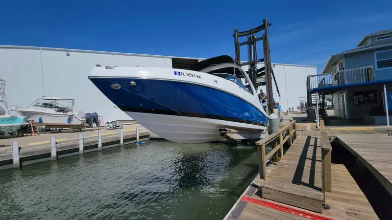 Slide: The Image of 2018 Rinker QX 26 boat being lifted from the water at a marina. - 28