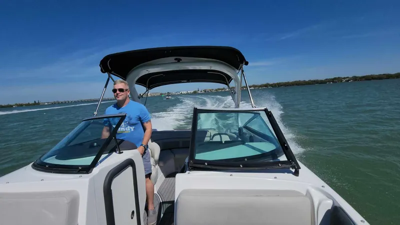 Slide: The Image of Man driving a 2018 Rinker QX 26 boat on a sunny day. - 47