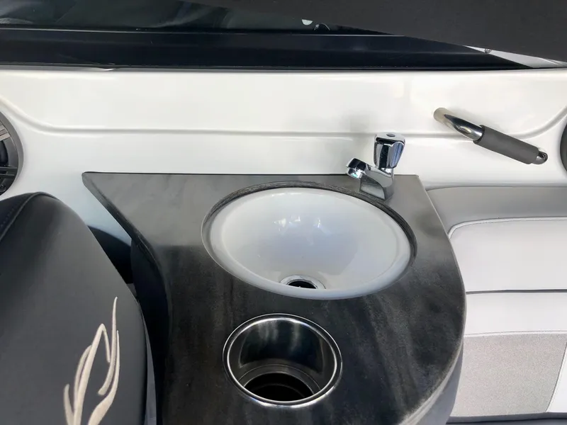 Slide: The Image of 2018 Rinker QX 26 boat interior with sink and cup holder. - 5