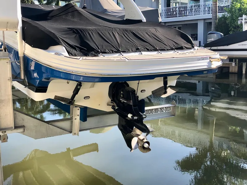Slide: The Image of 2018 Rinker QX 26 boat with black cover on a lift over water. - 9