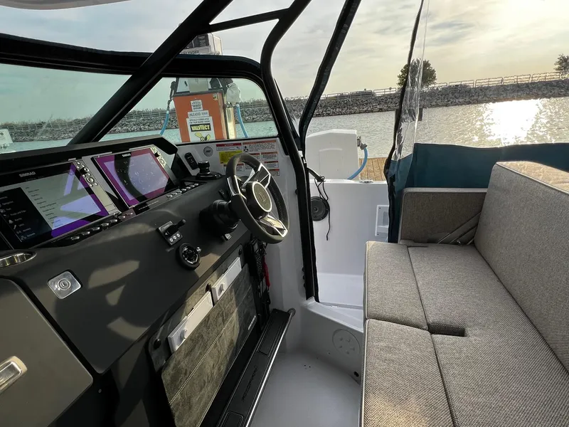 Slide: The Image of 2024 Axopar 37 Sun Top Mediterrana Edition interior with modern dashboard and seating by the water. - 16