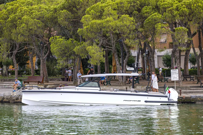 Slide: The Image of 2024 Axopar 37 Sun Top Mediterrana Edition boat docked near a tree-lined shore. - 52