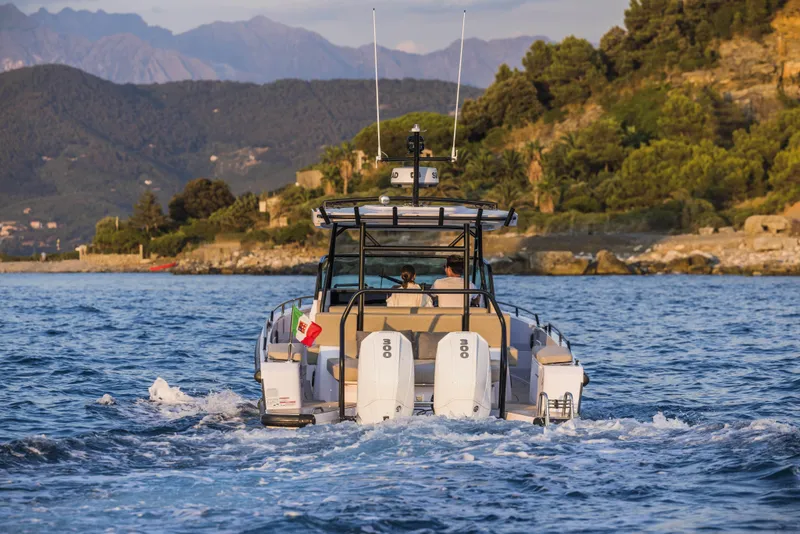 Slide: The Image of 2024 Axopar 37 Sun Top Mediterrana Edition cruising on water near scenic coastline. - 54
