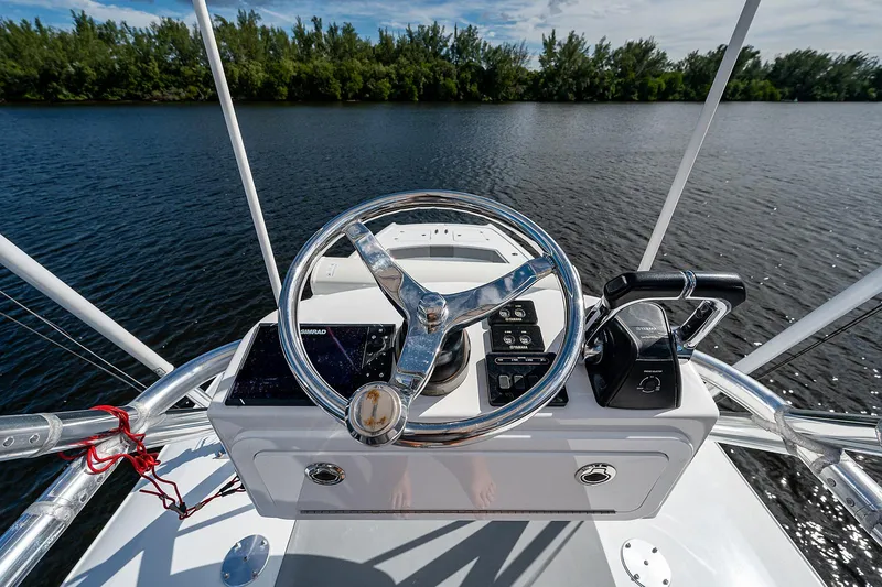 Slide: The Image of 2019 Freeman 37 boat helm with steering wheel and controls on a calm lake. - 3