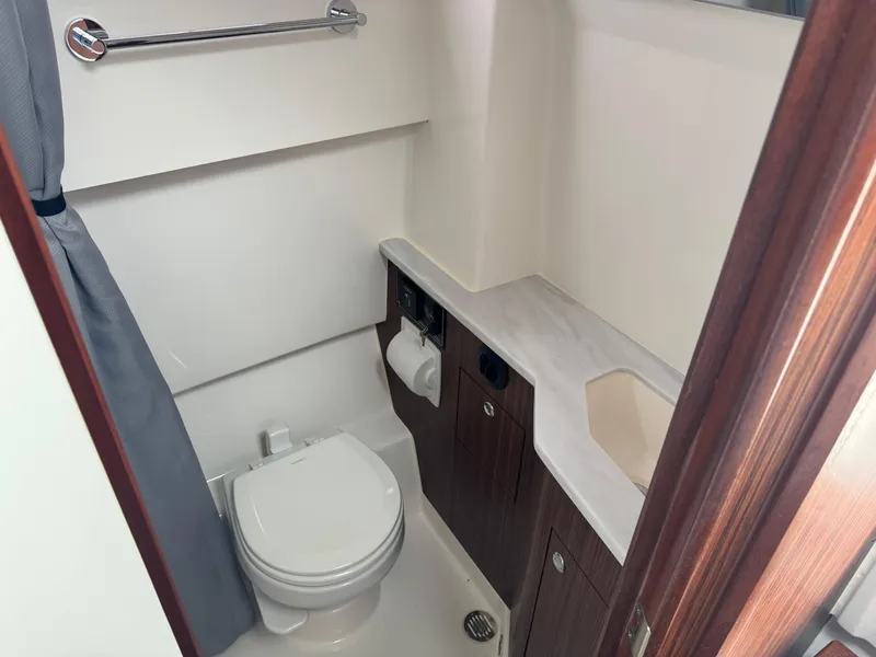 Slide: The Image of 2024 Pursuit S 358 Sport boat bathroom with toilet, sink, and storage cabinets. - 29
