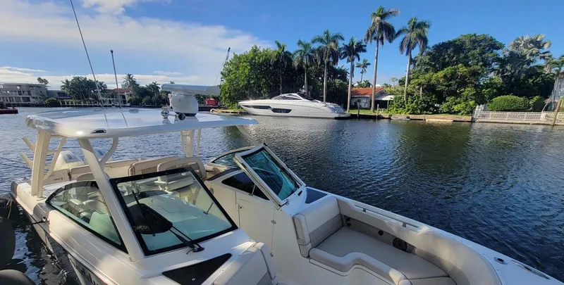 Slide: The Image of Boston Whaler 320 Vantage 2021 on calm water with palm trees in the background. - 3