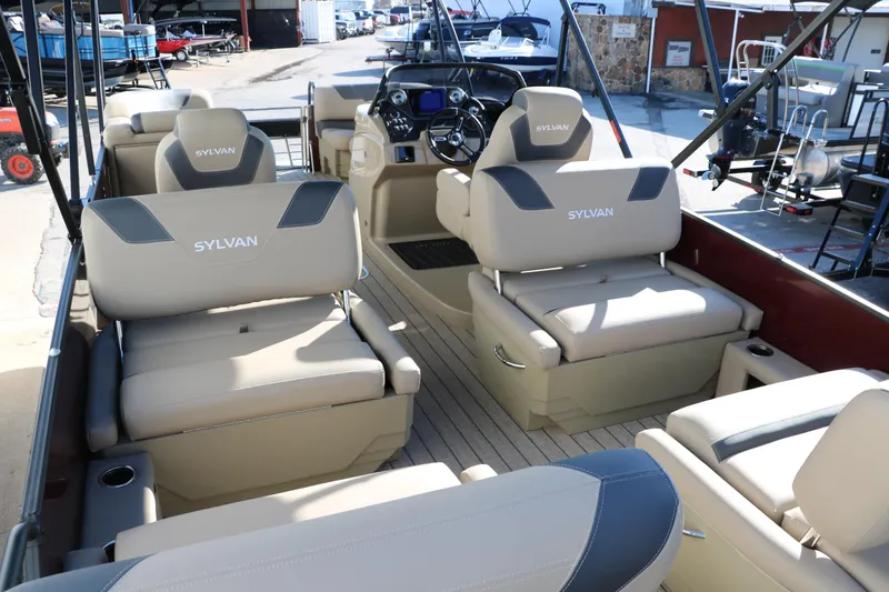 Slide: The Image of 2024 Sylvan L3 RLZ pontoon boat interior with beige seating and modern dashboard. - 18