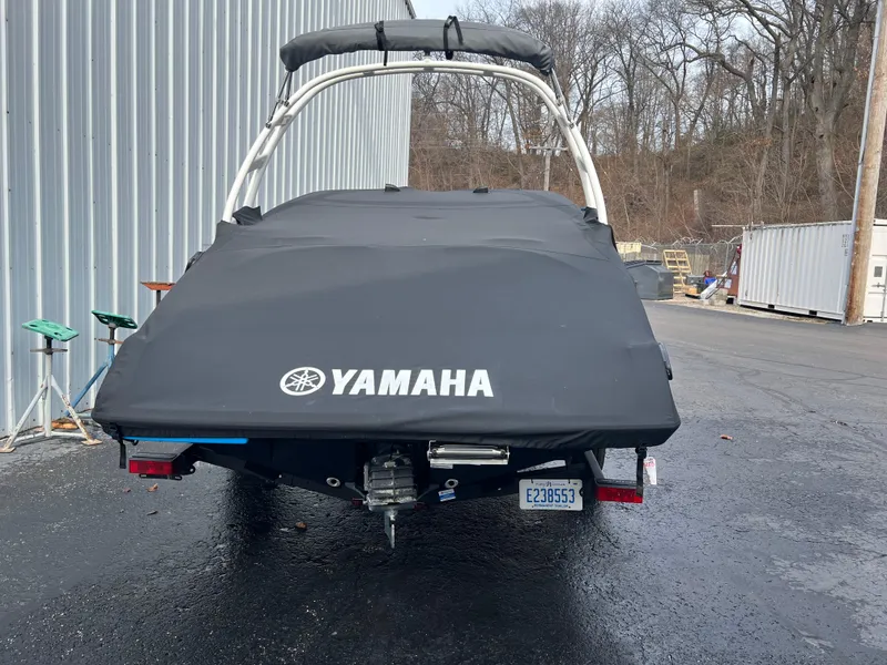 Slide: The Image of 2021 Yamaha Boats AR 195 covered and parked near a metal building. - 2