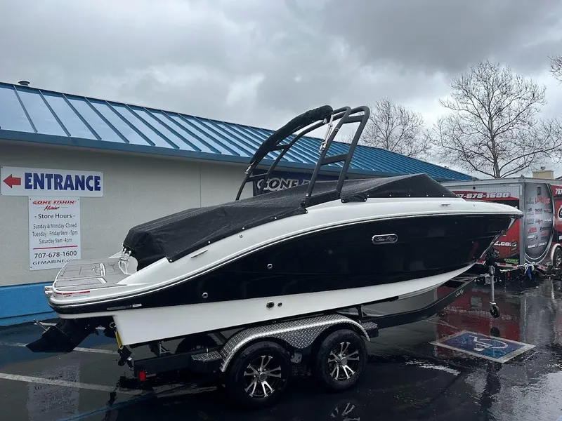 Slide: The Image of 2024 Sea Ray SPX 210 boat on trailer, black and white, parked outside dealership. - 2