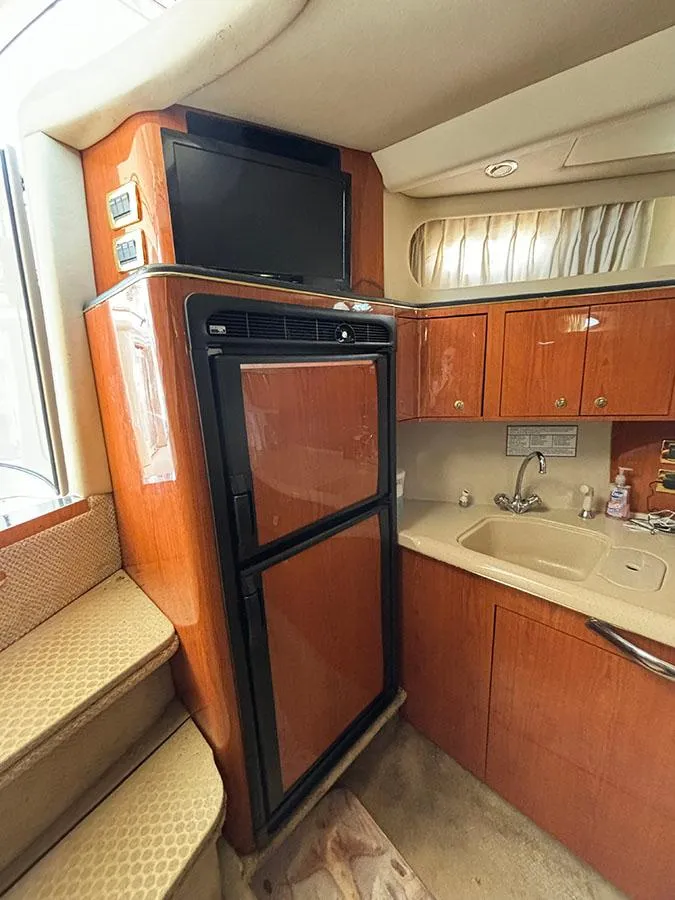 Slide: The Image of Interior of 2001 Sea Ray 410 Sundancer with kitchen area, fridge, and TV. - 26