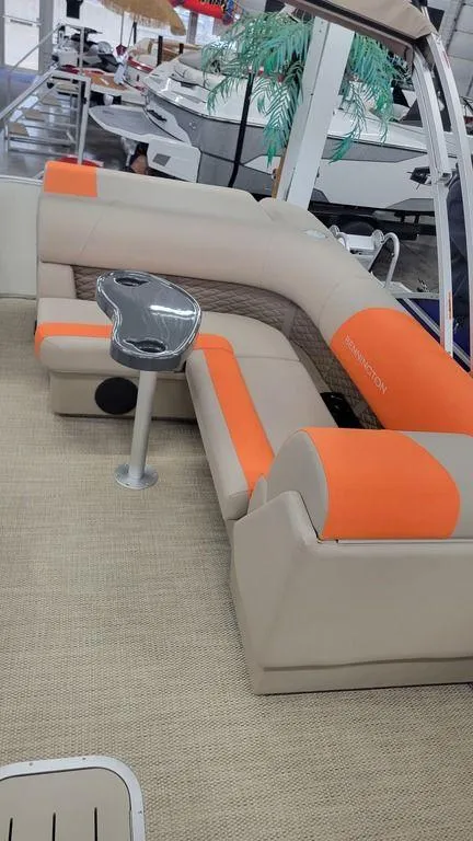 Slide: The Image of 2024 Bennington 20 SL pontoon boat with orange and beige seating. - 2