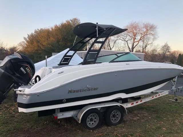 The Image of 2023 NauticStar 243DC Sport Deck boat on a trailer, side view. - 1