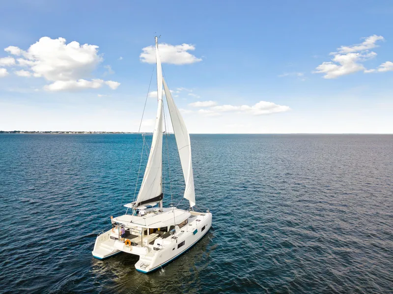 Slide: The Image of 2018 Lagoon 42 catamaran sailing on open water under a clear blue sky. - 12