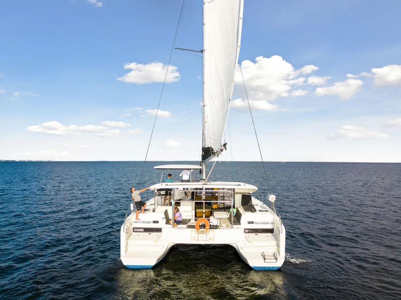 Slide: The Image of 2018 Lagoon 42 catamaran sailing on open water under a clear blue sky. - 16
