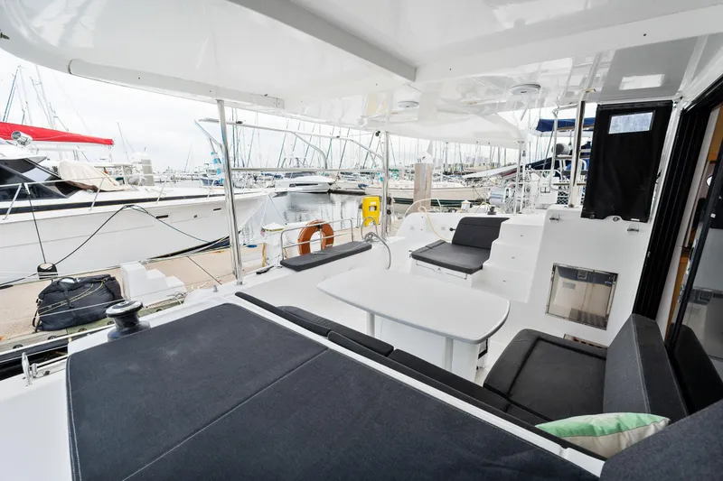 Slide: The Image of 2018 Lagoon 42 catamaran's spacious deck with seating and table, docked at marina. - 26