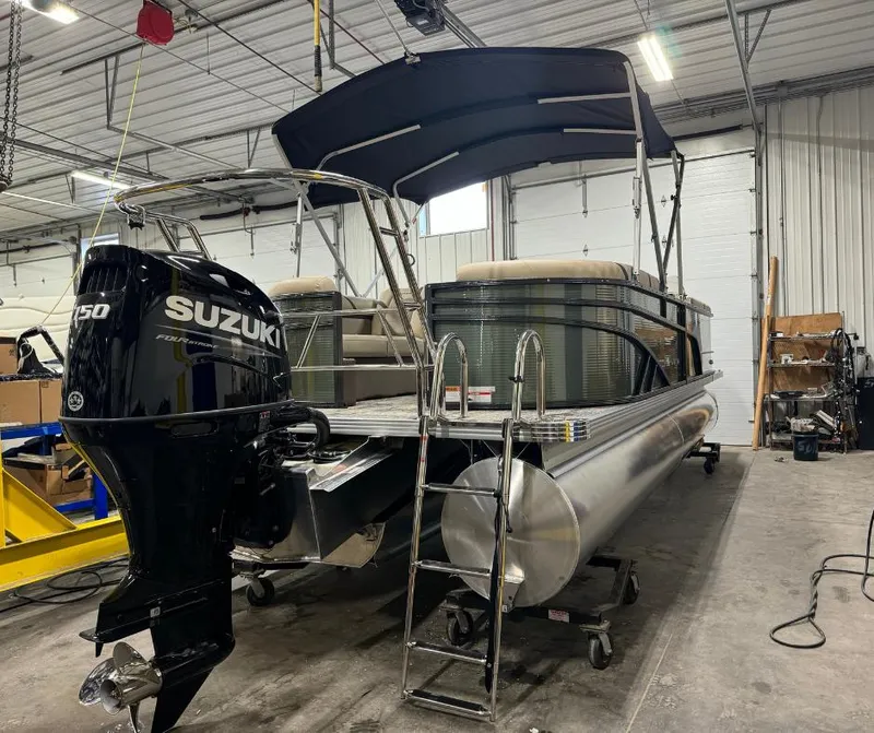 Slide: The Image of 2024 Crest Classic LX 240 pontoon boat with Suzuki outboard motor in a warehouse. - 1