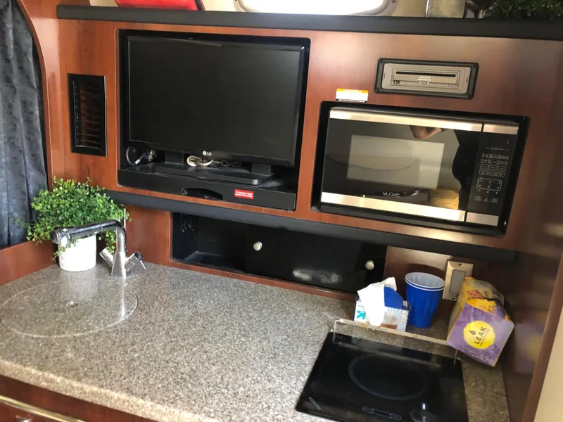 Slide: The Image of 2016 Chaparral 290 Signature interior kitchen with TV, microwave, and countertop appliances. - 24