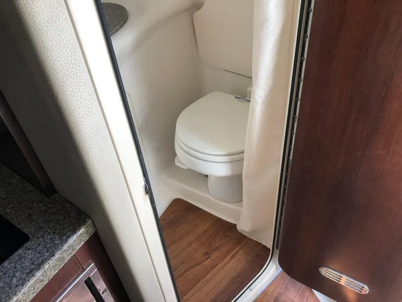Slide: The Image of 2016 Chaparral 290 Signature boat bathroom with wooden flooring and compact toilet. - 28