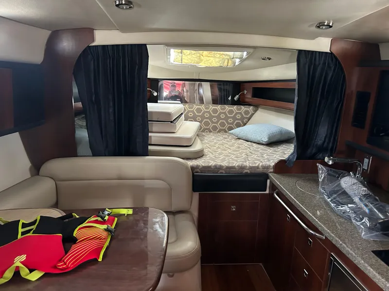 Slide: The Image of 2016 Chaparral 290 Signature cabin interior with seating, bed, and kitchenette. - 34