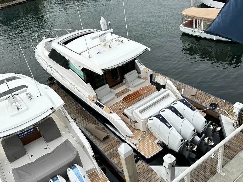 Slide: The Image of 2024 Tiara Yachts 48 LE docked, featuring triple outboard engines and spacious deck. - 40