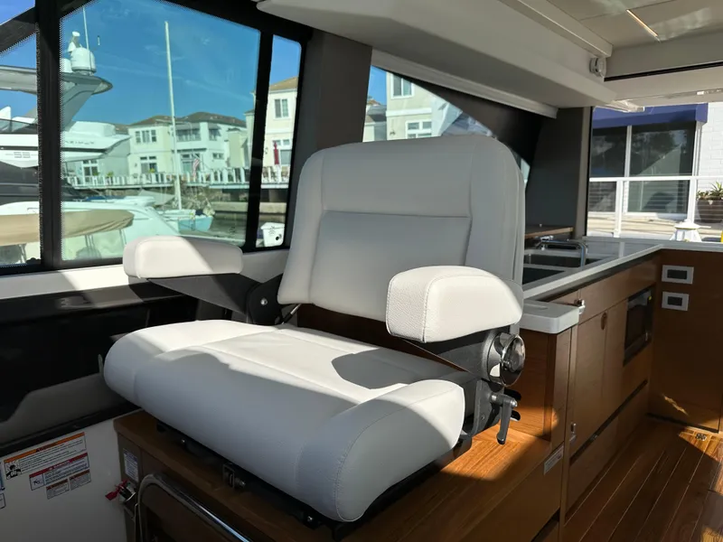 Slide: The Image of 2024 Tiara Yachts 48 LE interior with white captain's chair and wooden cabinetry. - 45