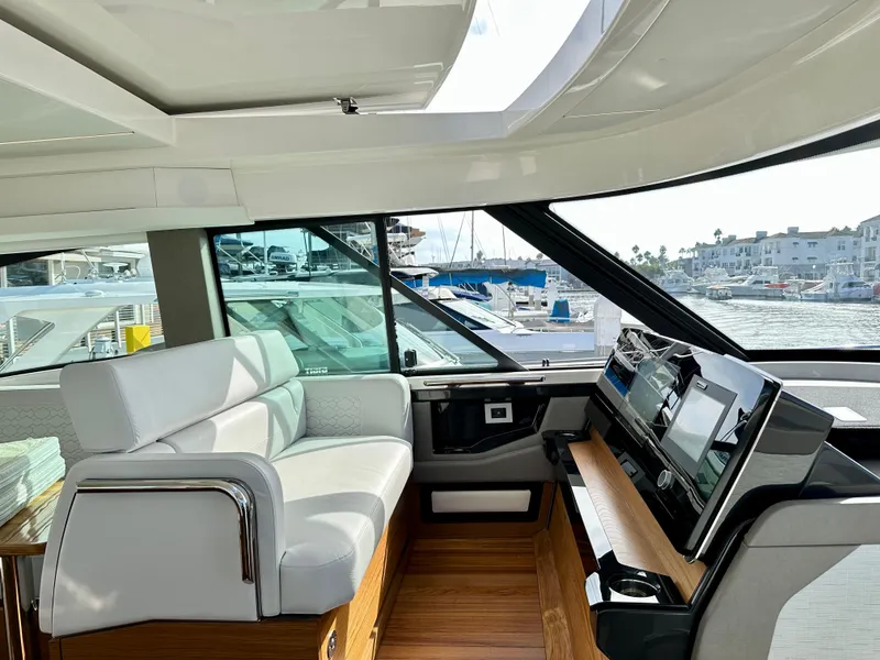 Slide: The Image of 2024 Tiara Yachts 48 LE interior with modern helm and seating, docked at marina. - 46