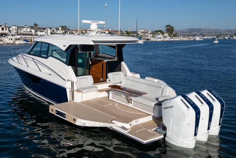 Slide: The Image of 2024 Tiara Yachts 48 LE luxury boat with triple Mercury engines on a serene waterway. - 7