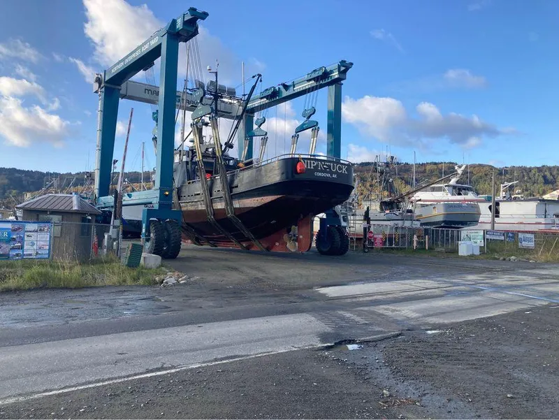 Slide: The Image of A 1979 custom longline tender crabber boat in a shipyard lift under a blue sky. - 11