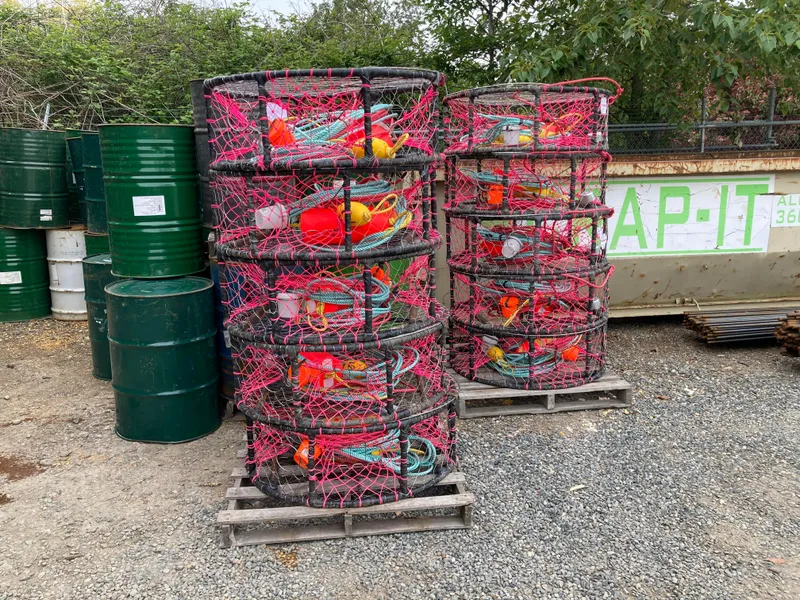 Slide: The Image of Stacks of crab pots with colorful buoys and nets, next to green barrels. - 9